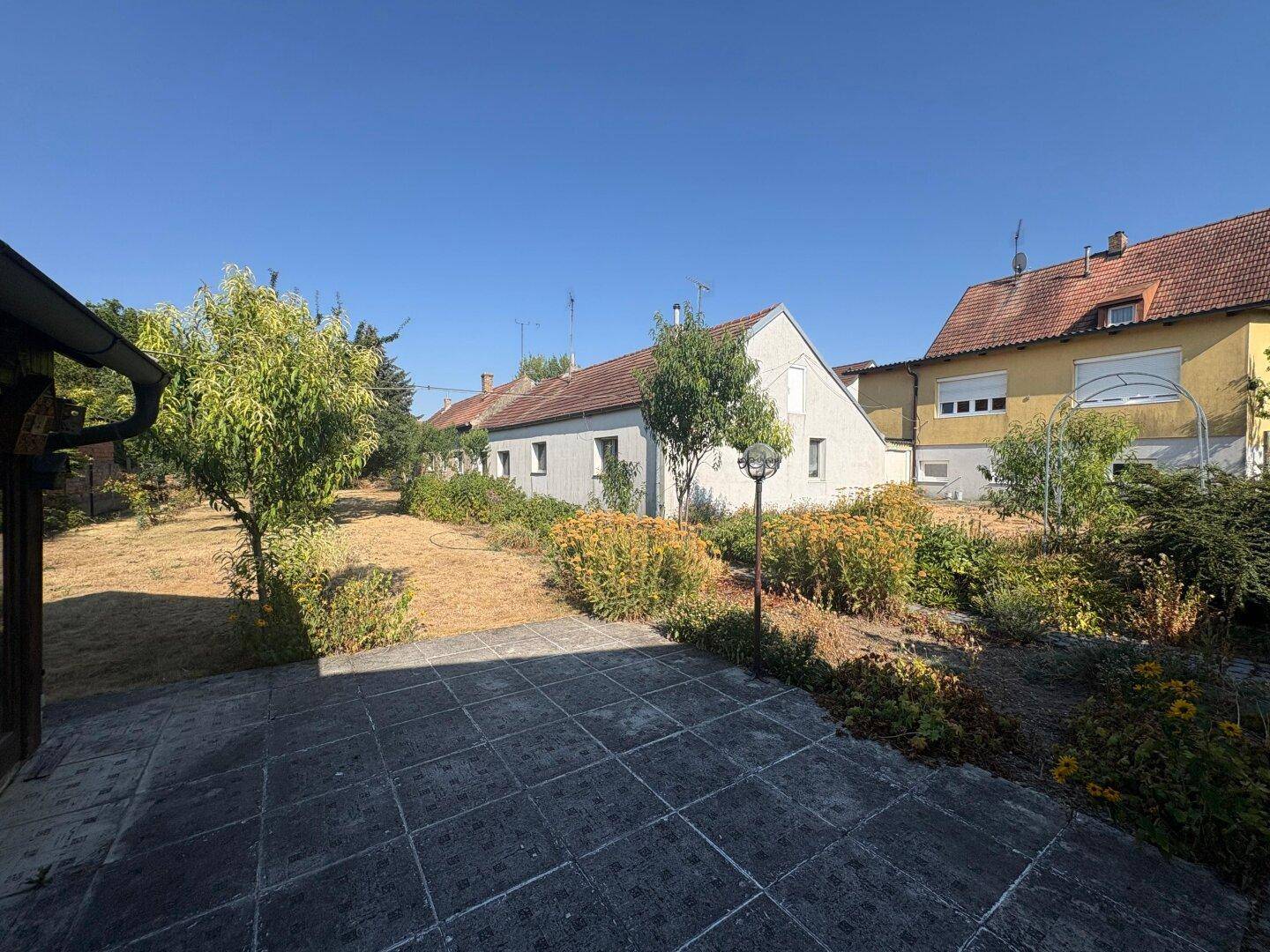 Gepflasterte Terrasse mit Gartenbeleuchtung und Blick auf den Gartenbereich.