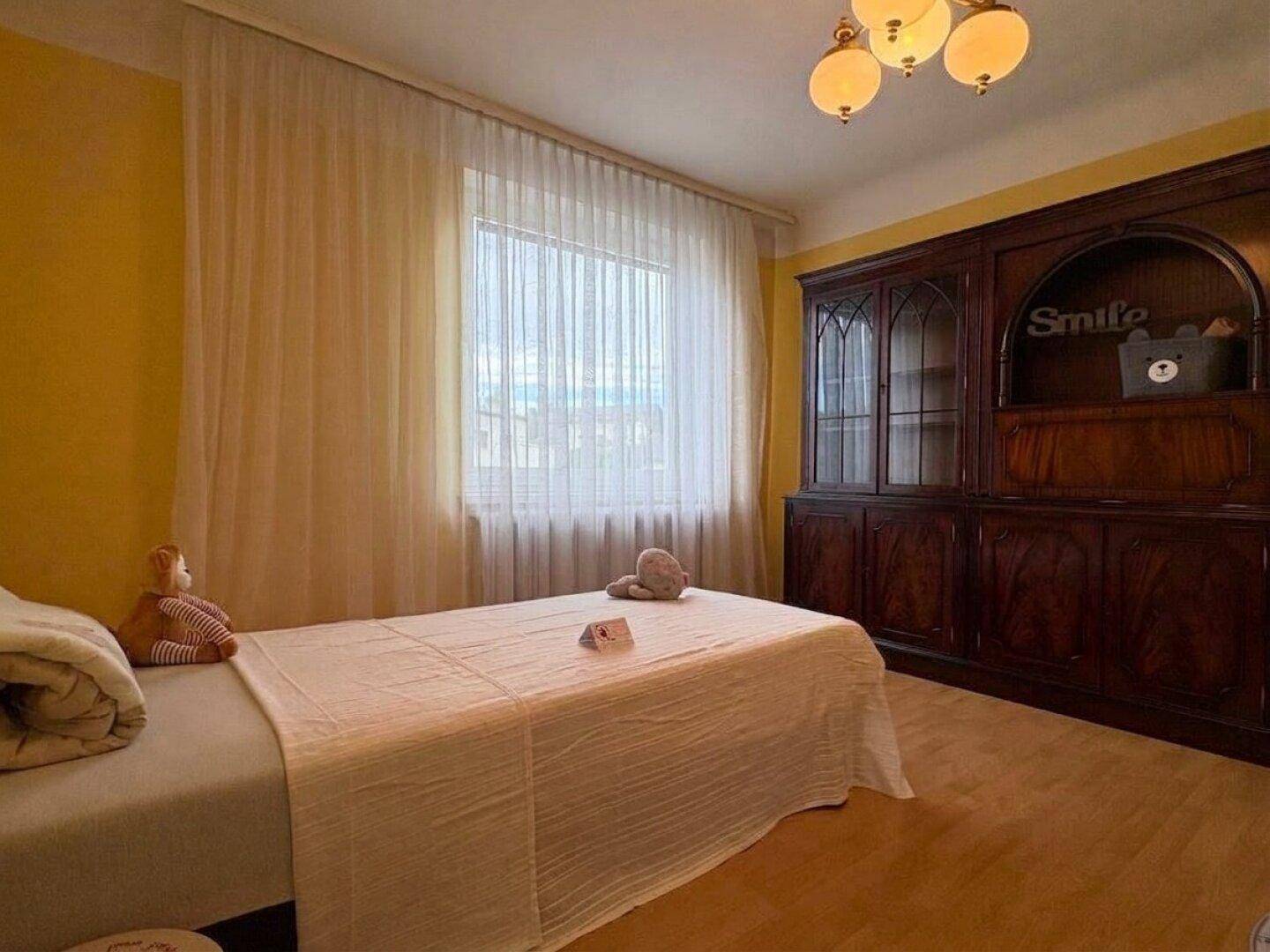Schlafzimmer mit Einzelbett, Holzboden und großem Holzschrank.