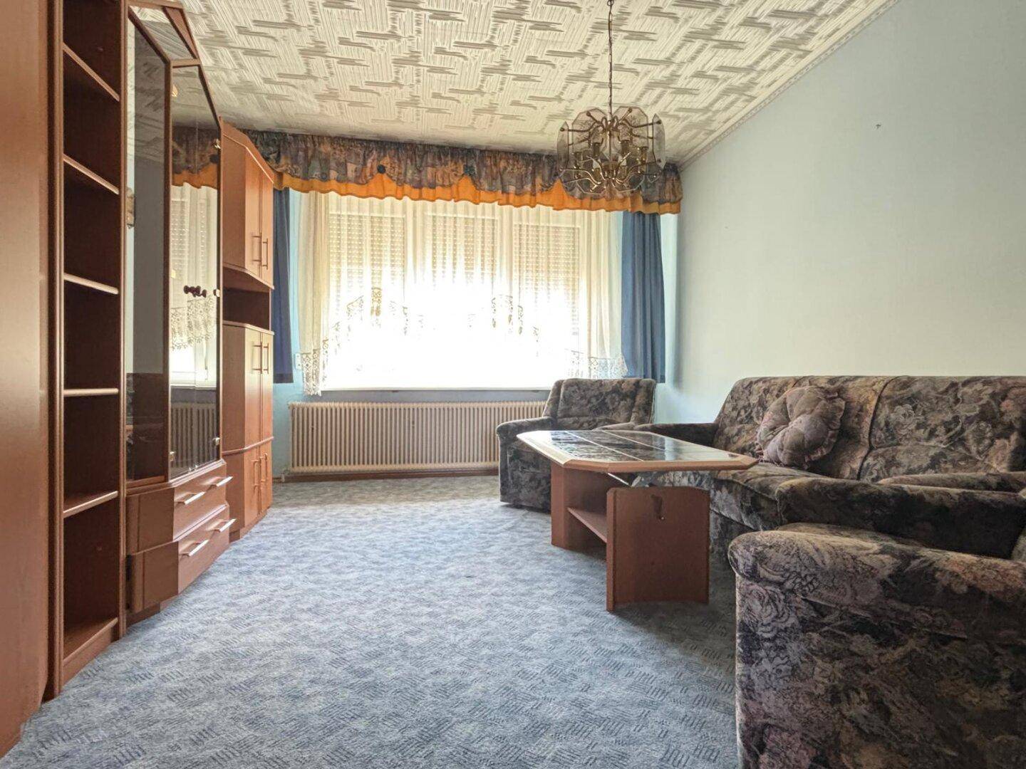 Wohnzimmer mit Teppichboden, Schrankwand und Sofa in traditionellem Stil.