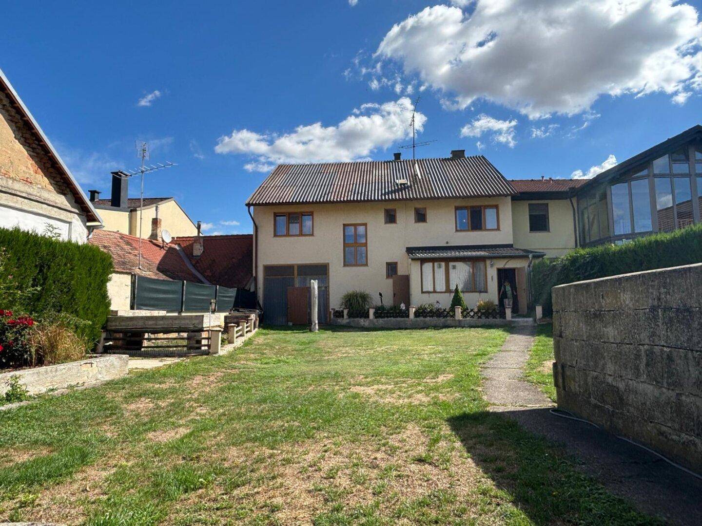 Großer Garten hinter dem Haus mit Rasenfläche und Nebengebäuden.