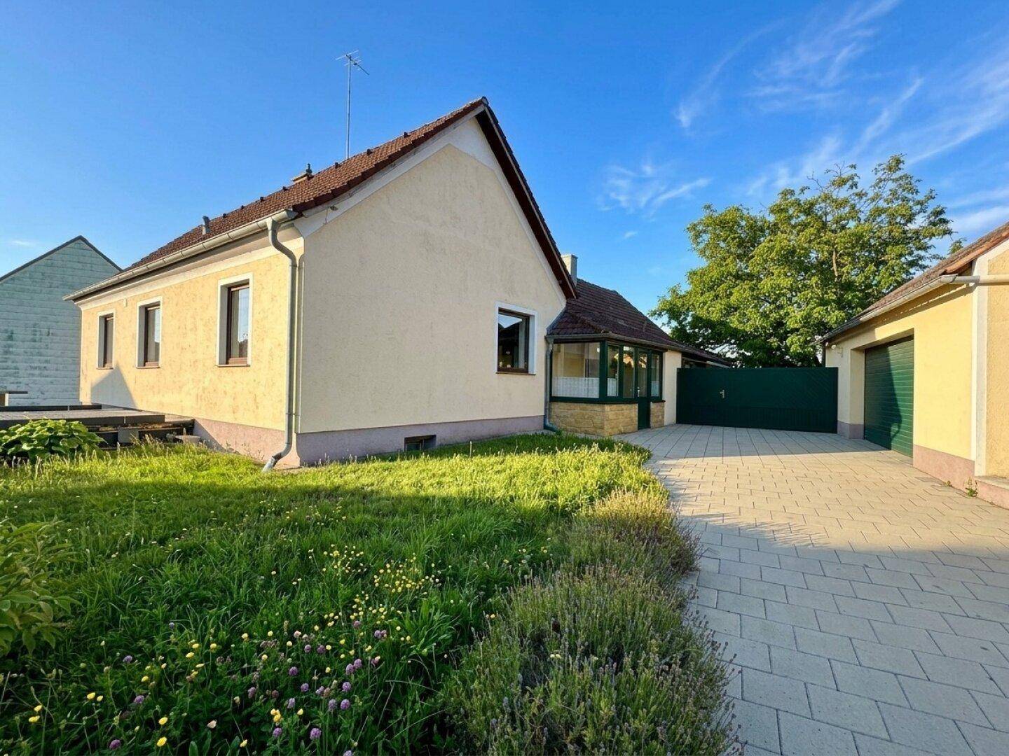 Seitenansicht des Hauses mit Gartenbereich, Einfahrt und Garage im Hintergrund.