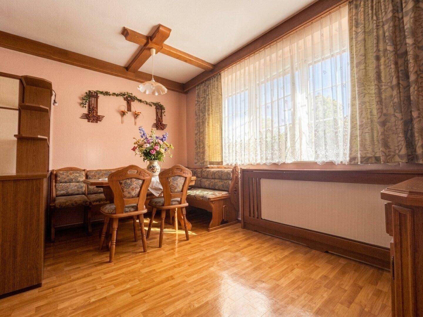 Heller Essbereich mit Eckbank, Holztisch und großen Fenstern.