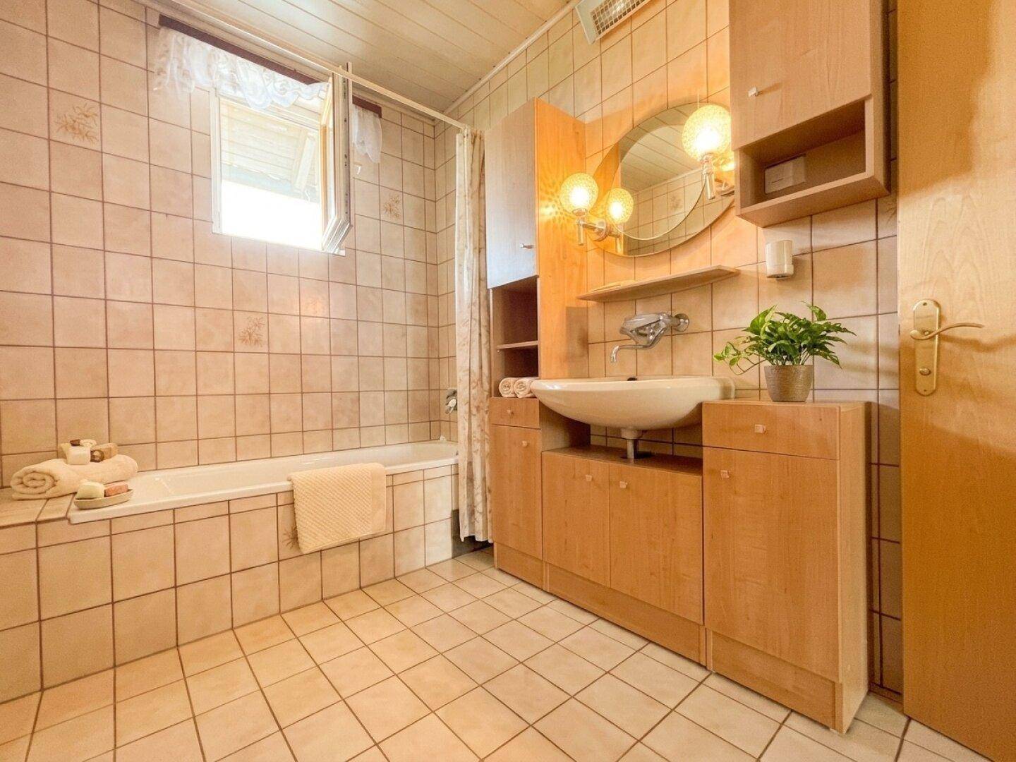 Badezimmer mit Badewanne, Waschbecken und Holzmöbeln.