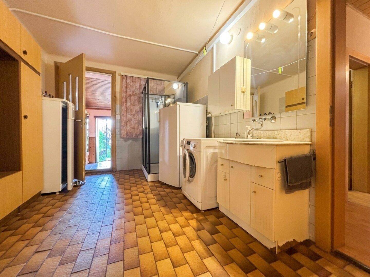 Geräumiger Hauswirtschaftsraum mit Waschmaschine, Dusche und Waschbecken.