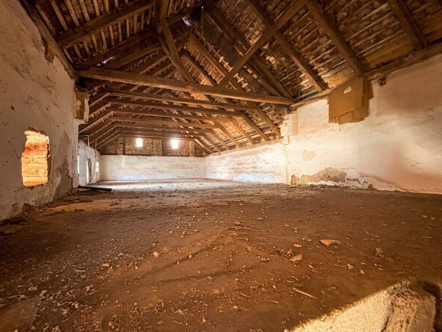 Geräumiger Dachboden mit sichtbaren Holzbalken und viel Potenzial.