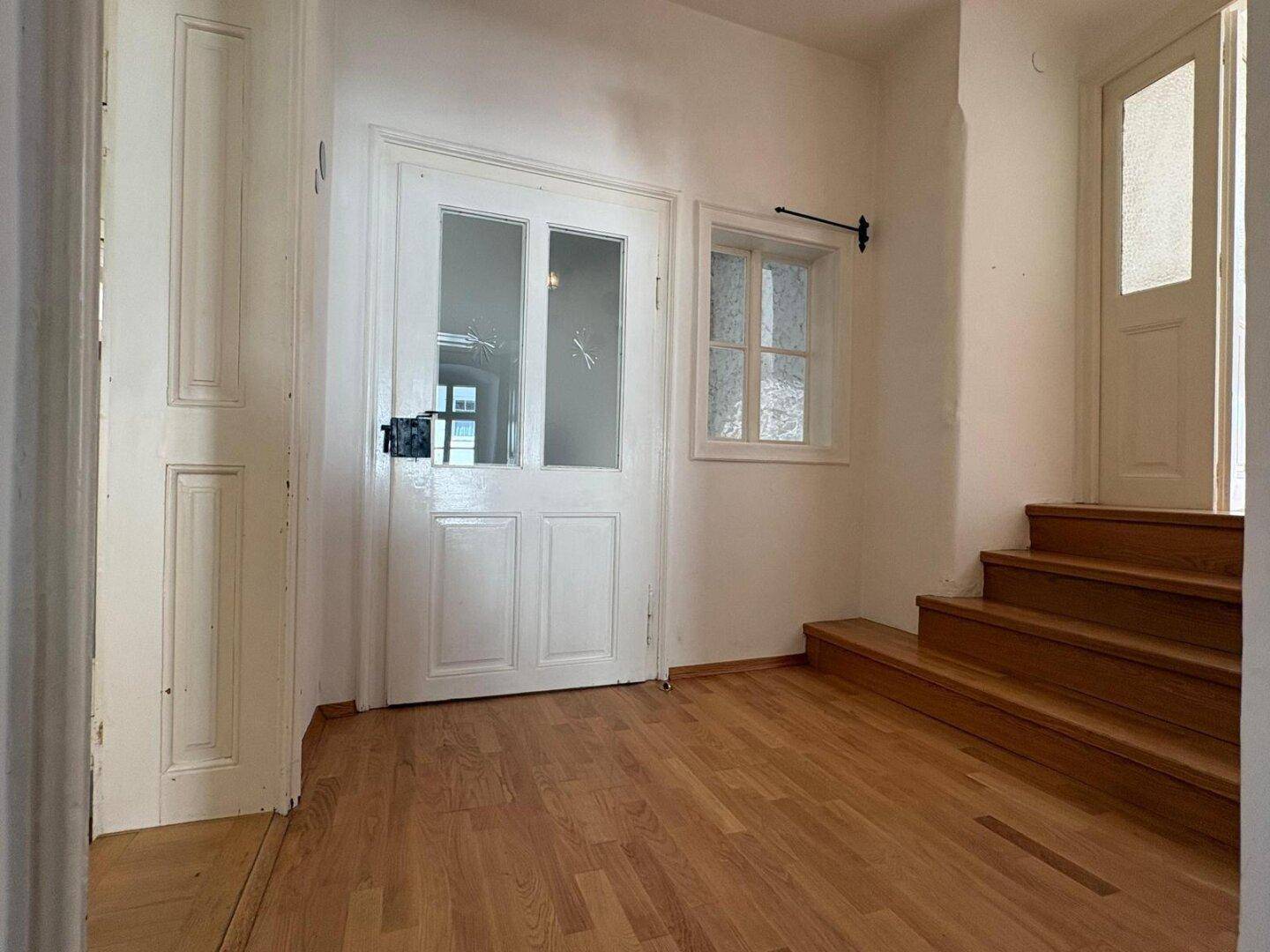 Geräumiger Flur mit Holzboden und Treppe, die in die obere Etage führt.