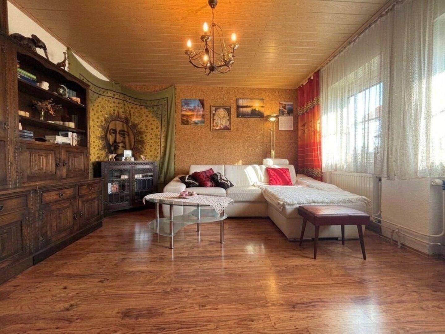Gemütliches Wohnzimmer mit Holzboden, weißem Sofa und rustikalen Holzmöbeln.