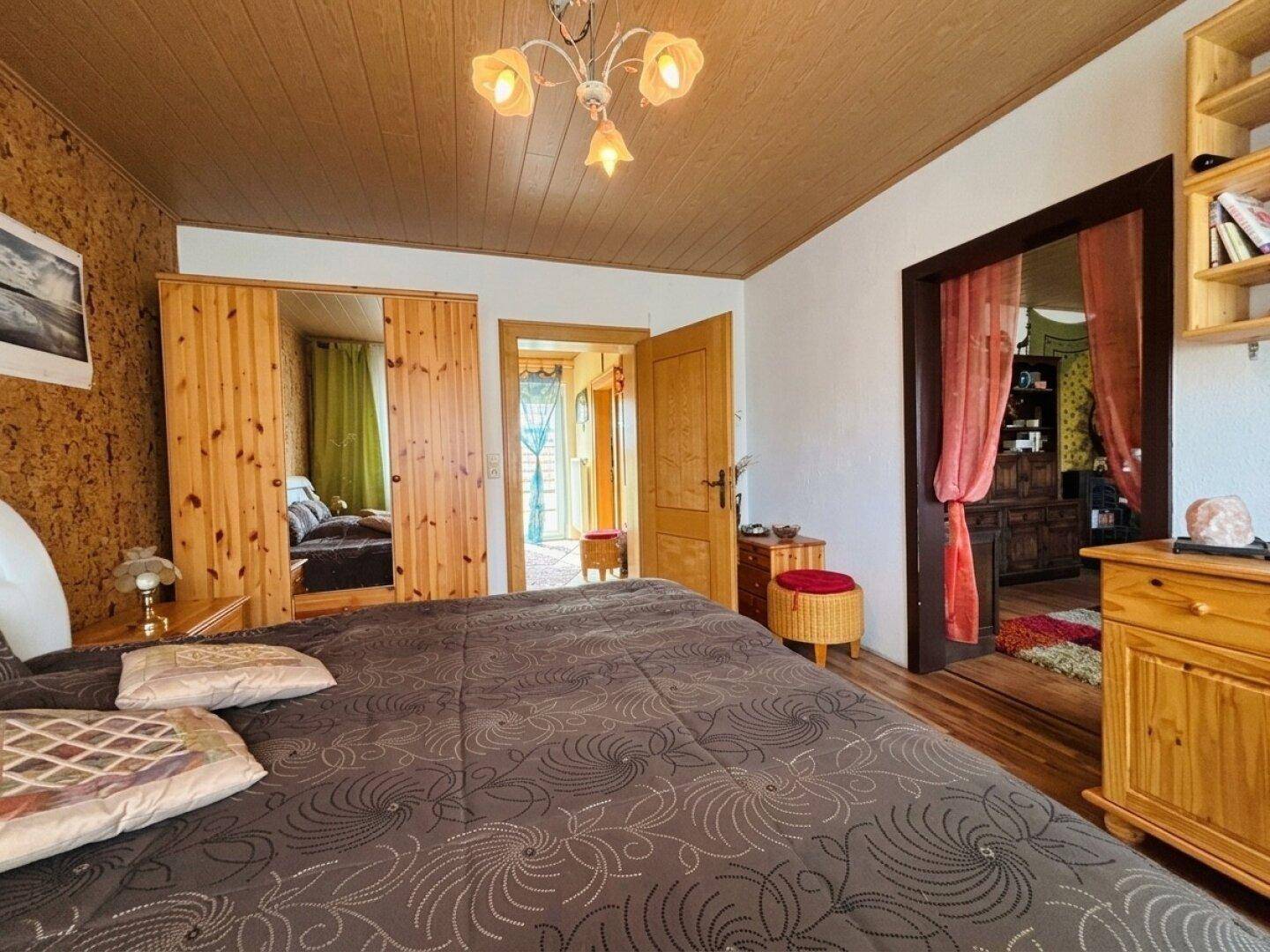 Schlafzimmer mit Holzschrank und Zugang zu weiteren Räumen, bietet viel Stauraum.
