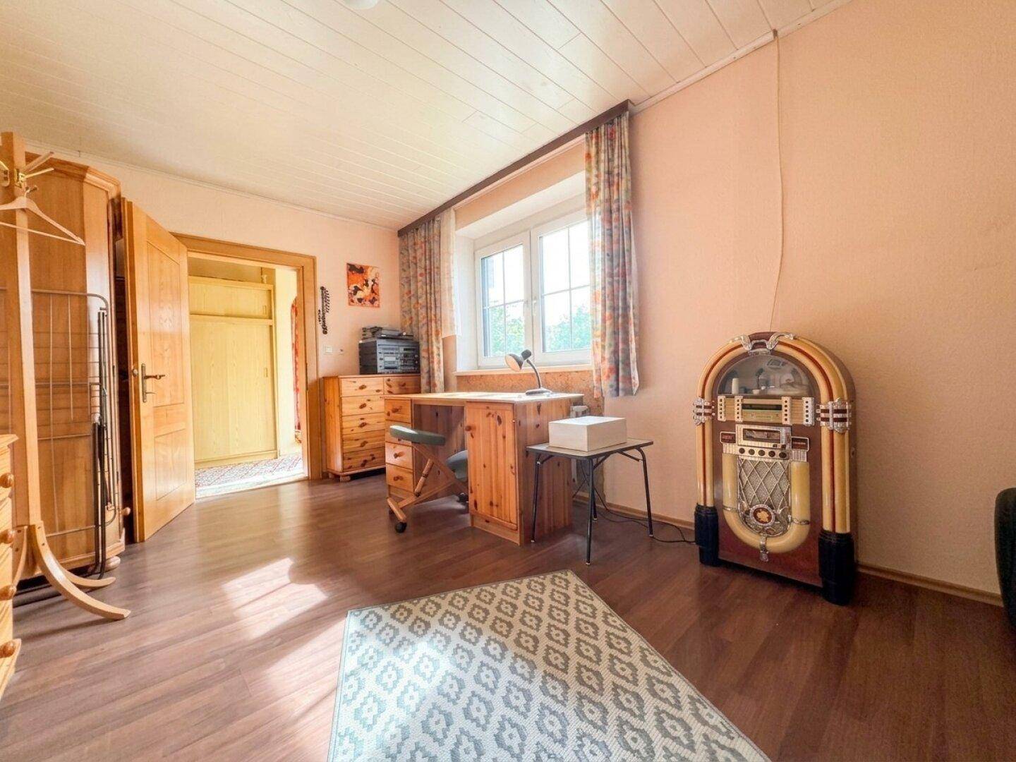 Helles Arbeitszimmer mit Holzboden, Schreibtisch und einem dekorativen Jukebox-Element.
