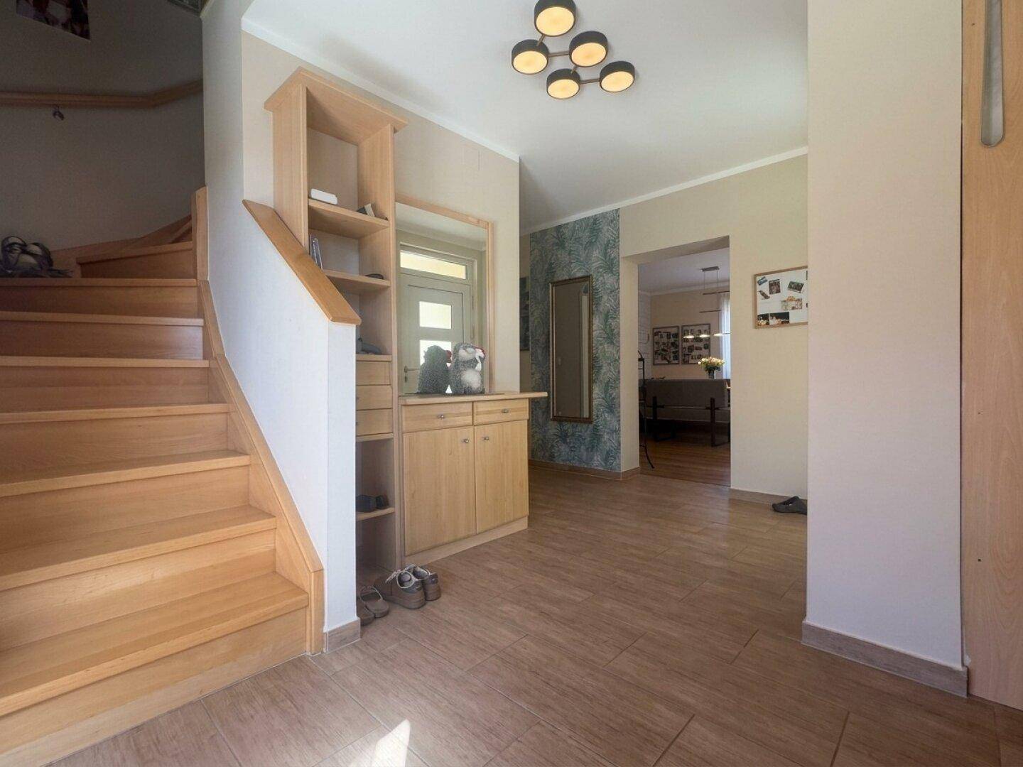Eingangsbereich mit Holztreppe, Garderobe und Blick in den Wohnbereich.