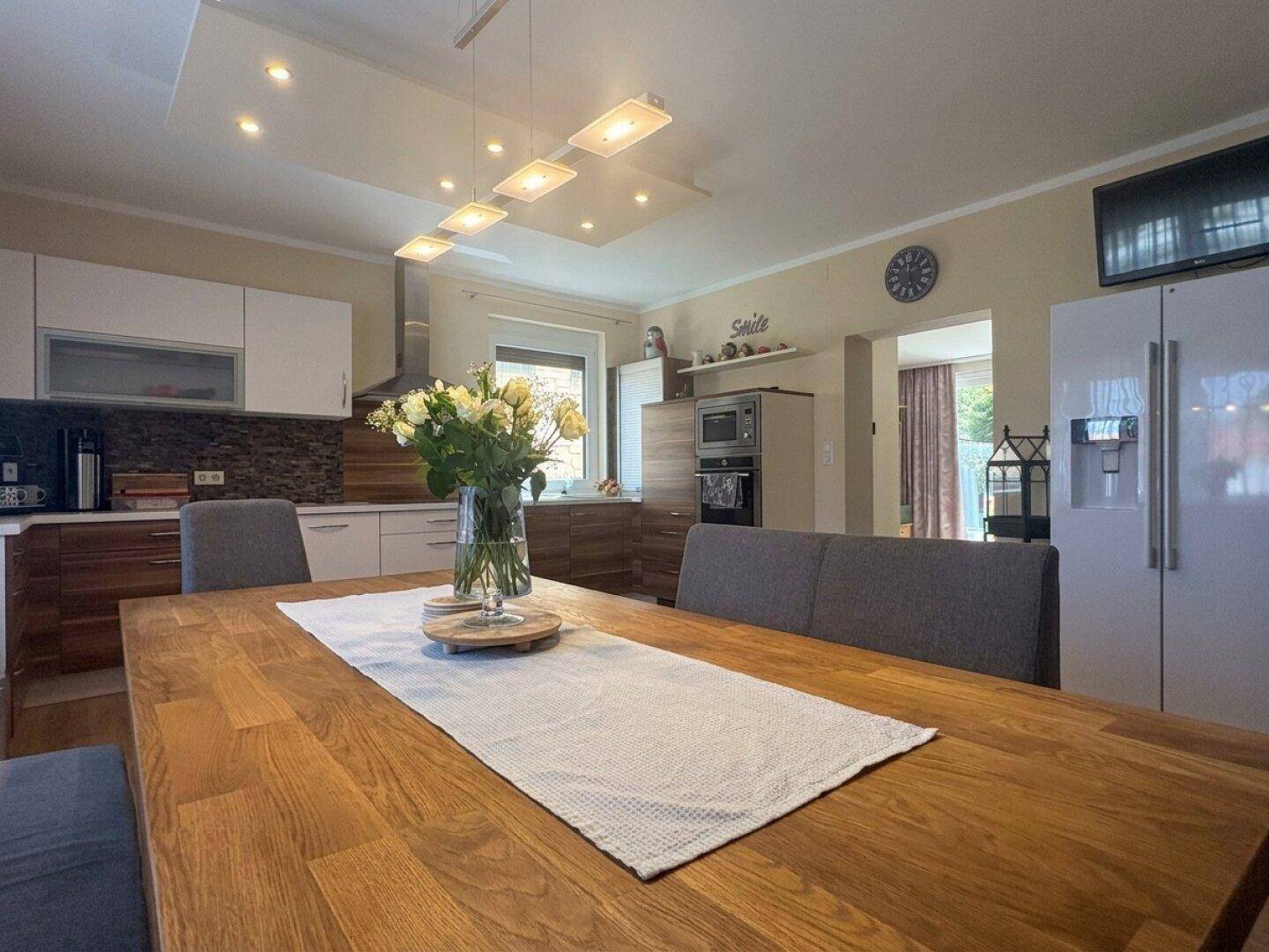 Moderne Küche mit Holztisch, Einbaugeräten und Blick in den Essbereich.