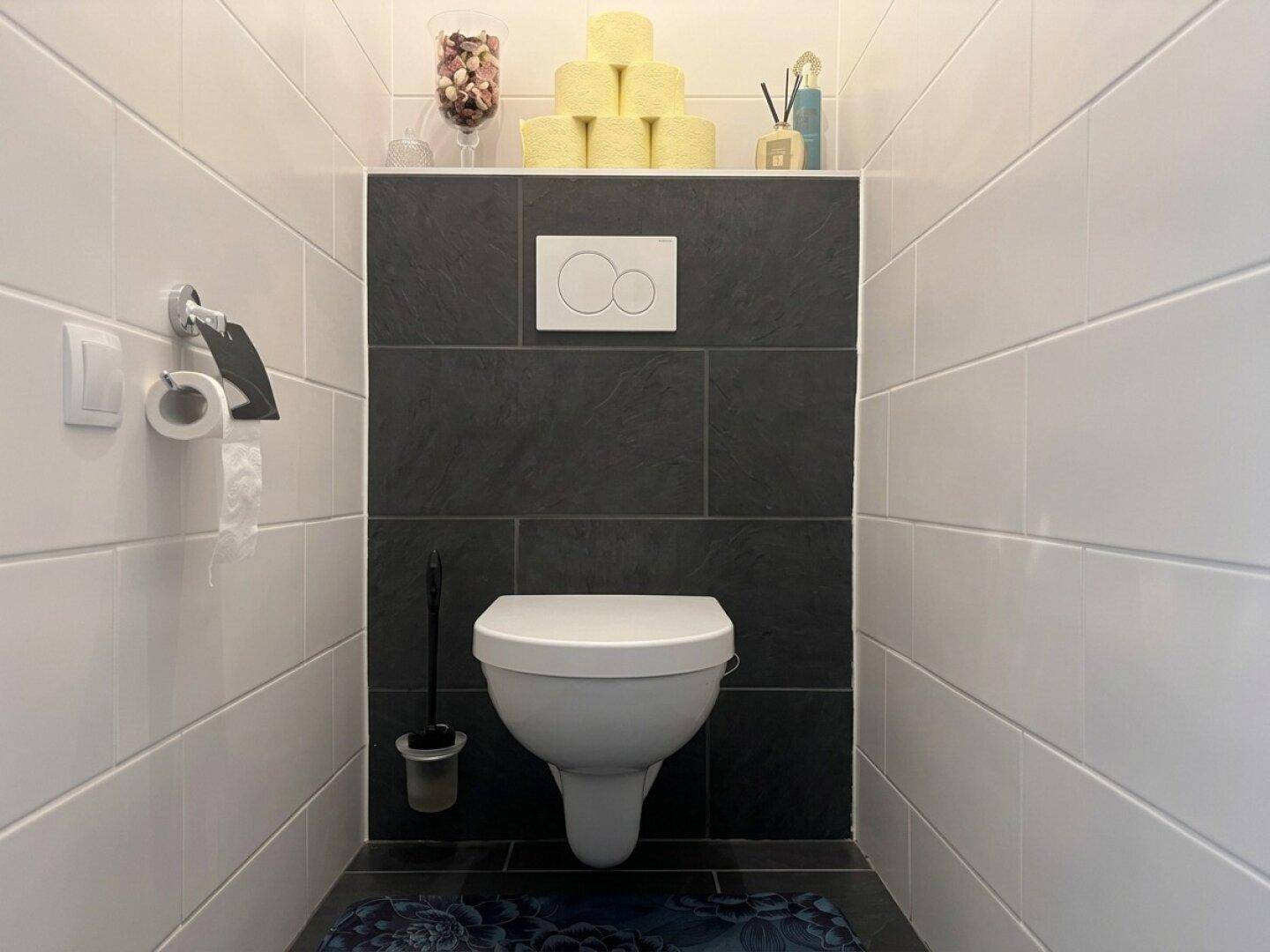 Modernes Gäste-WC mit Wand-WC und dunklen Akzentfliesen.
