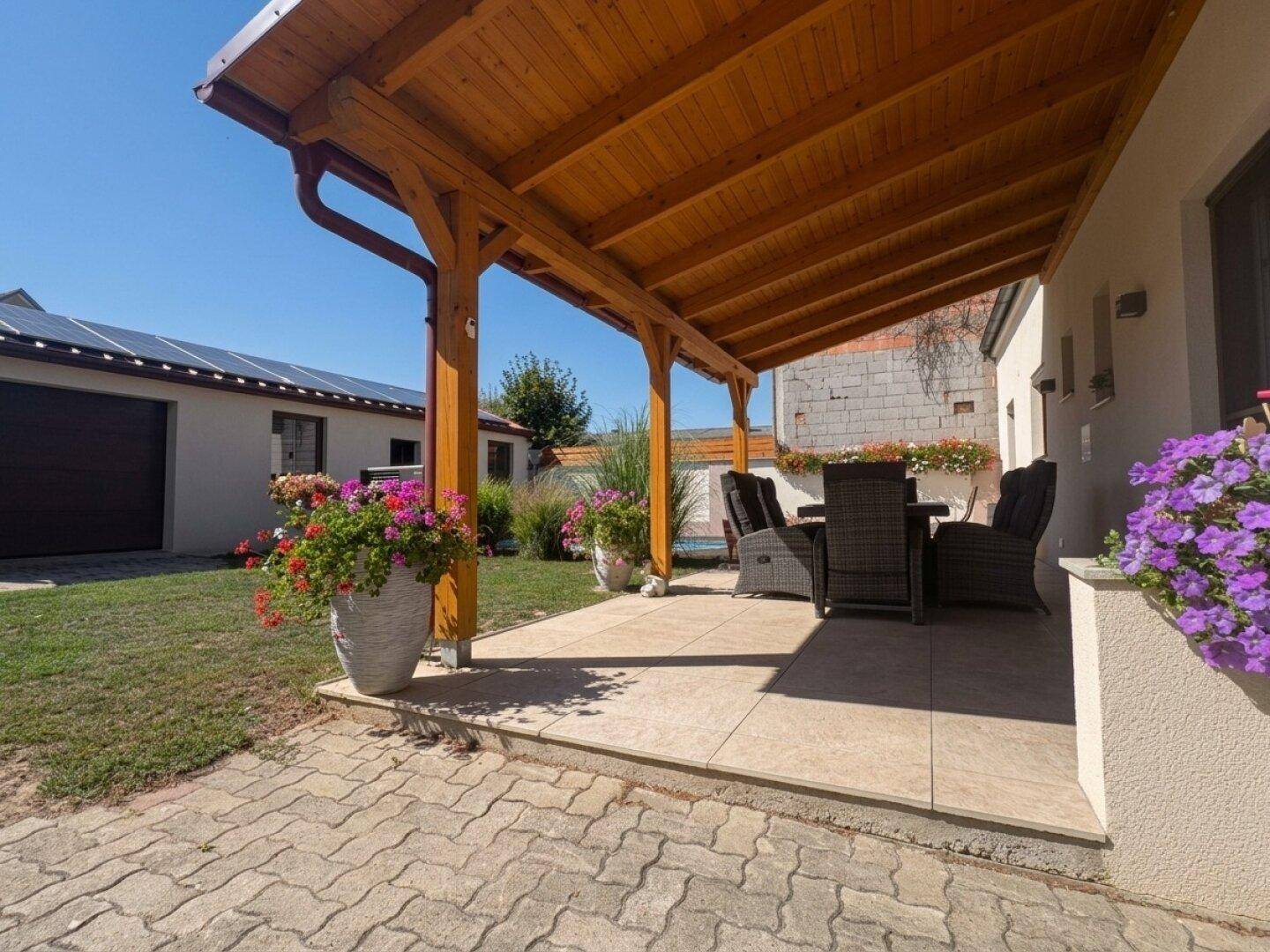 Überdachte Terrasse mit Sitzgelegenheiten und Blick auf den Garten.