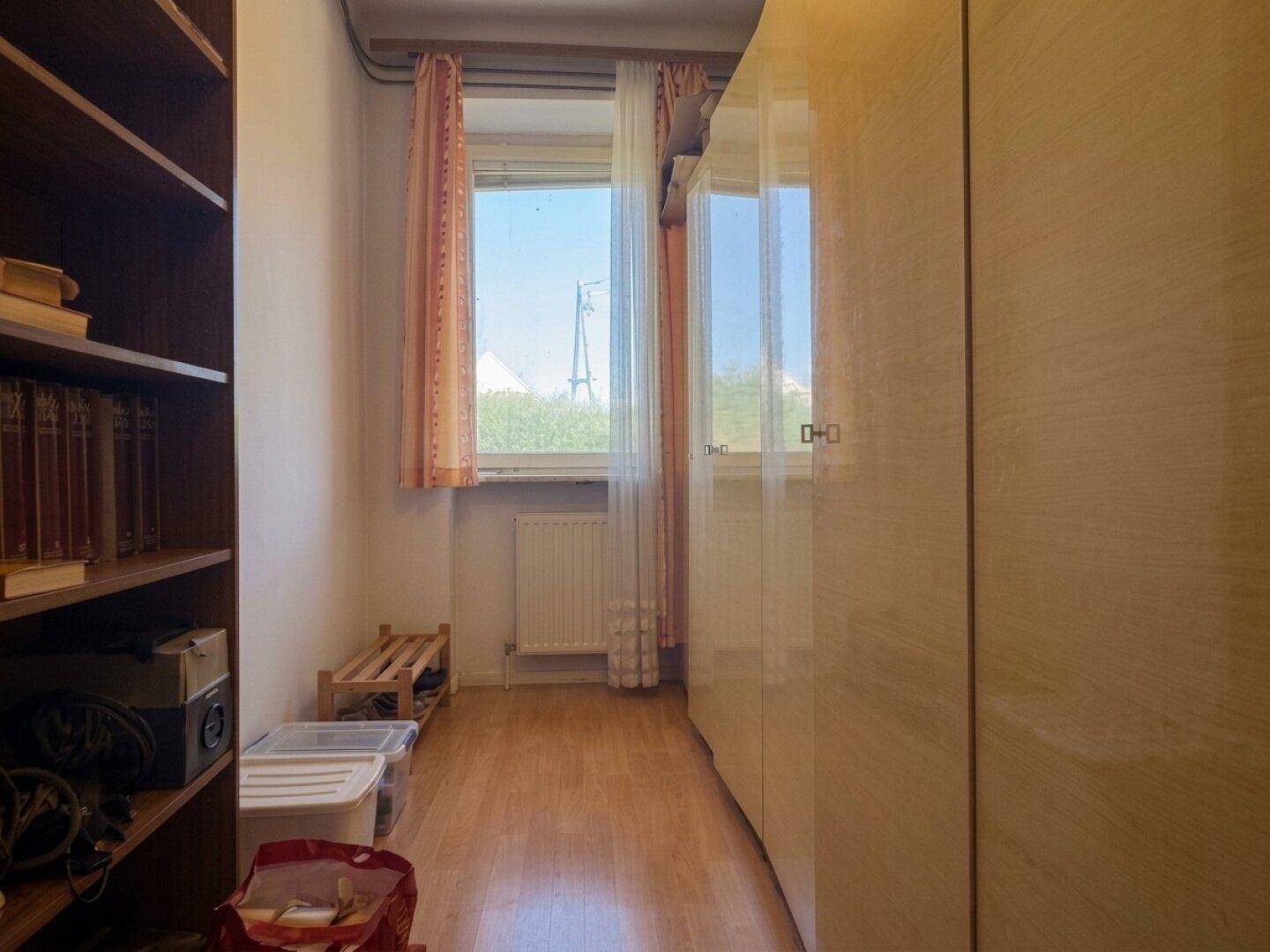 Raum mit Holzfußboden, einem Fenster und integrierten Kleiderschränken.