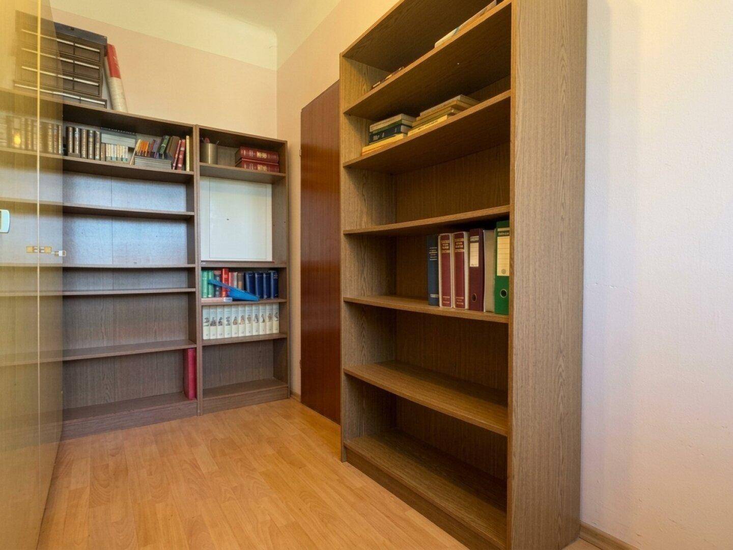 Arbeitszimmer mit Holzfußboden und mehreren Bücherregalen, ideal für eine Bibliothek.