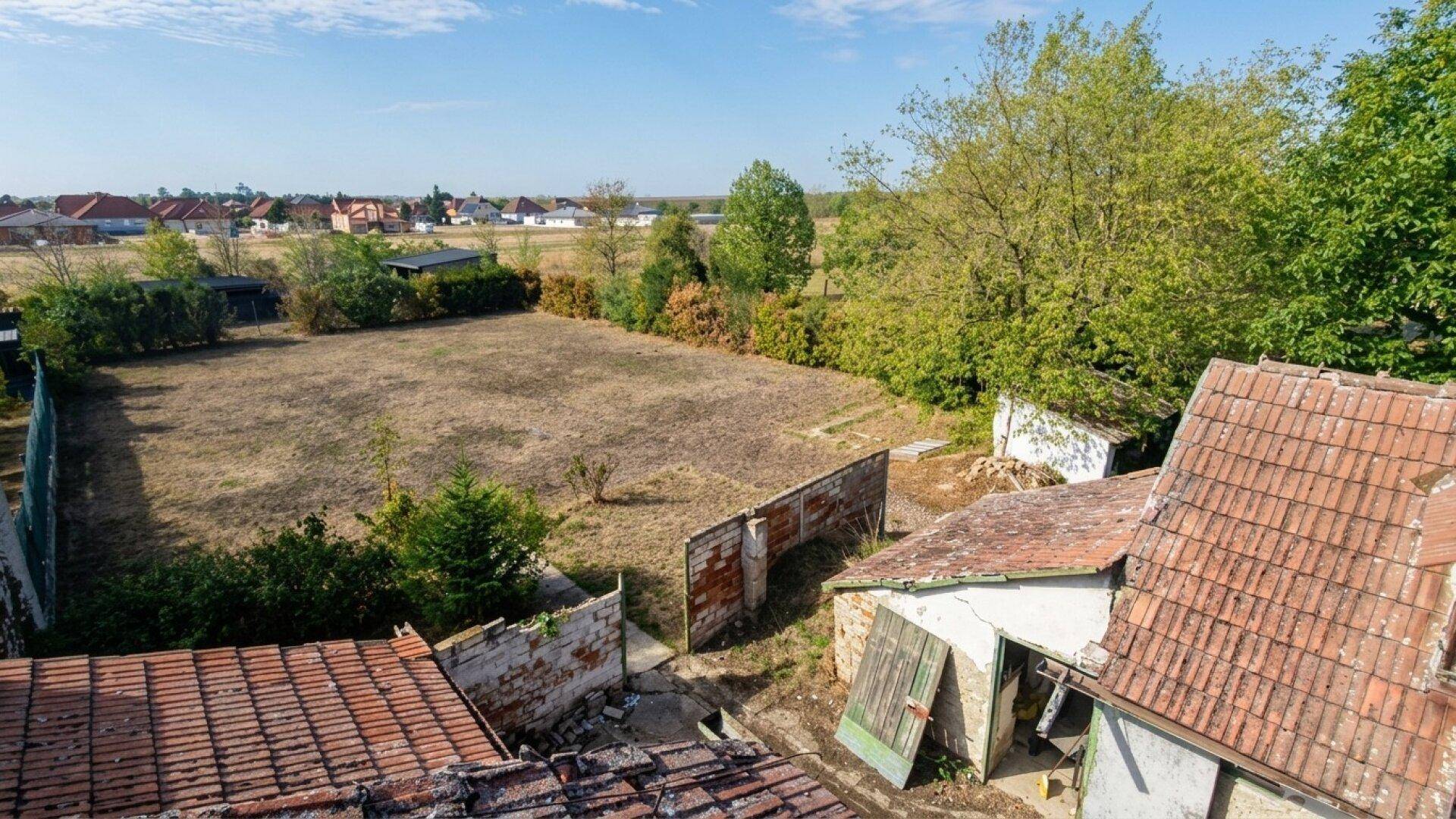 Erhöhte Ansicht des Anwesens mit trockenem Feld, Nebengebäuden und umliegenden Häusern.