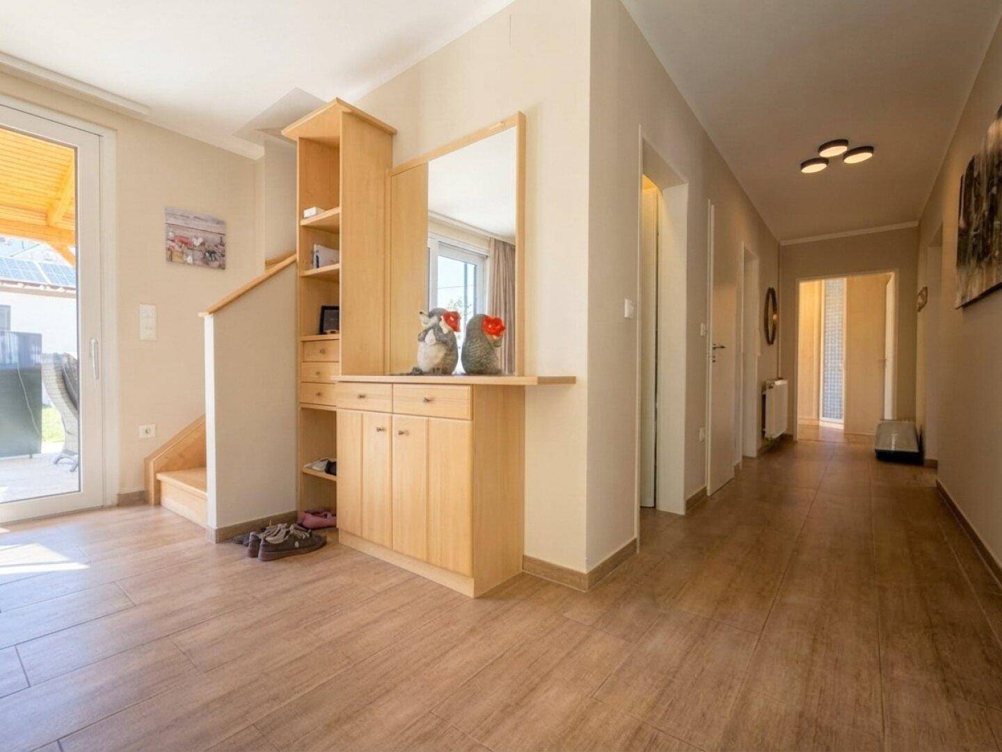 Heller Flur mit Holzoptik-Fliesen, Garderobe und Zugang zu weiteren Räumen sowie zum Garten.