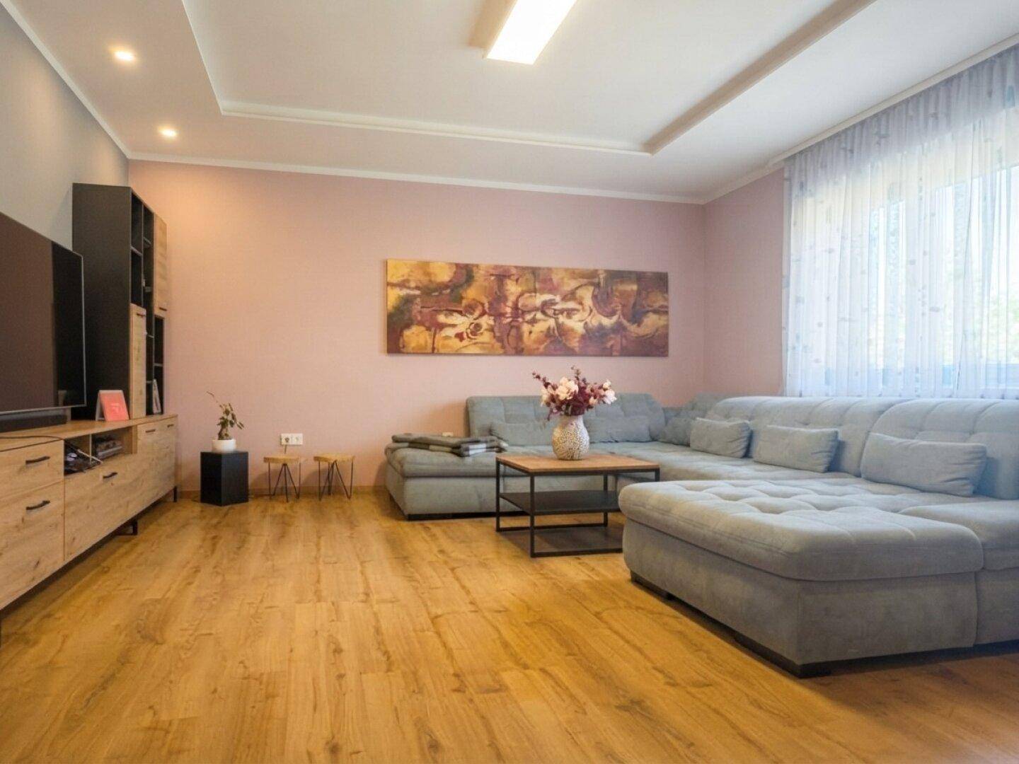 Gemütliches Wohnzimmer mit großem Ecksofa, Holzboden und moderner Einrichtung.