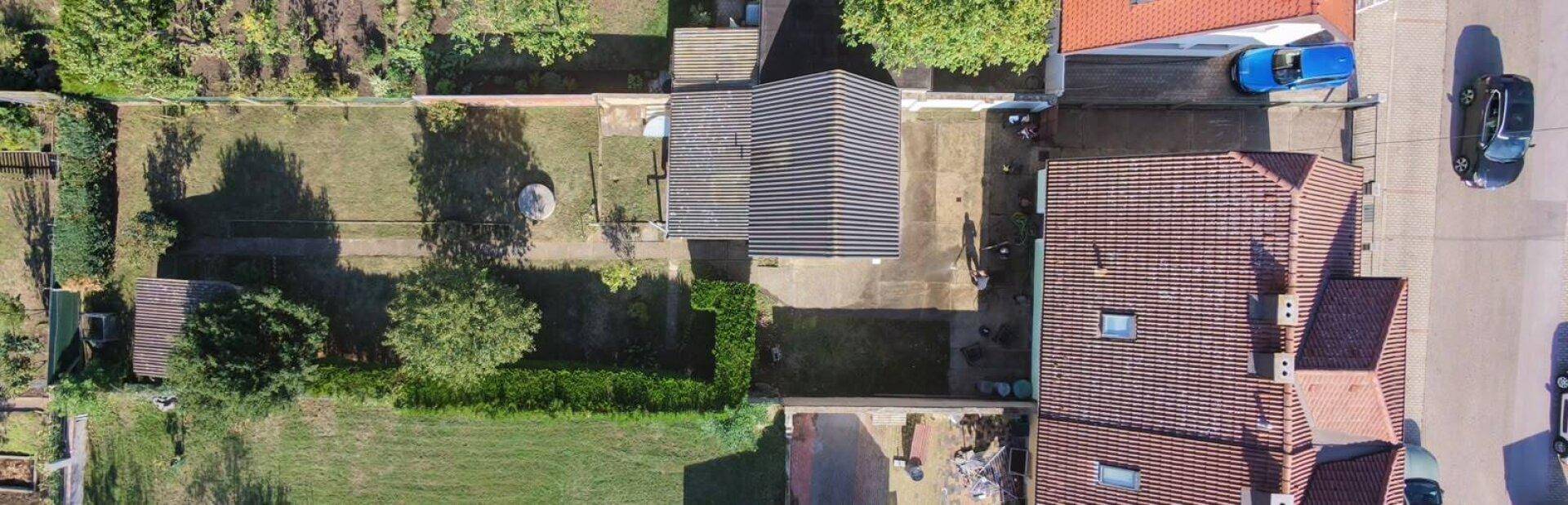 Luftaufnahme eines Wohnhauses mit Garten, Nebengebäuden und angrenzenden Grundstücken in einer Siedlung.