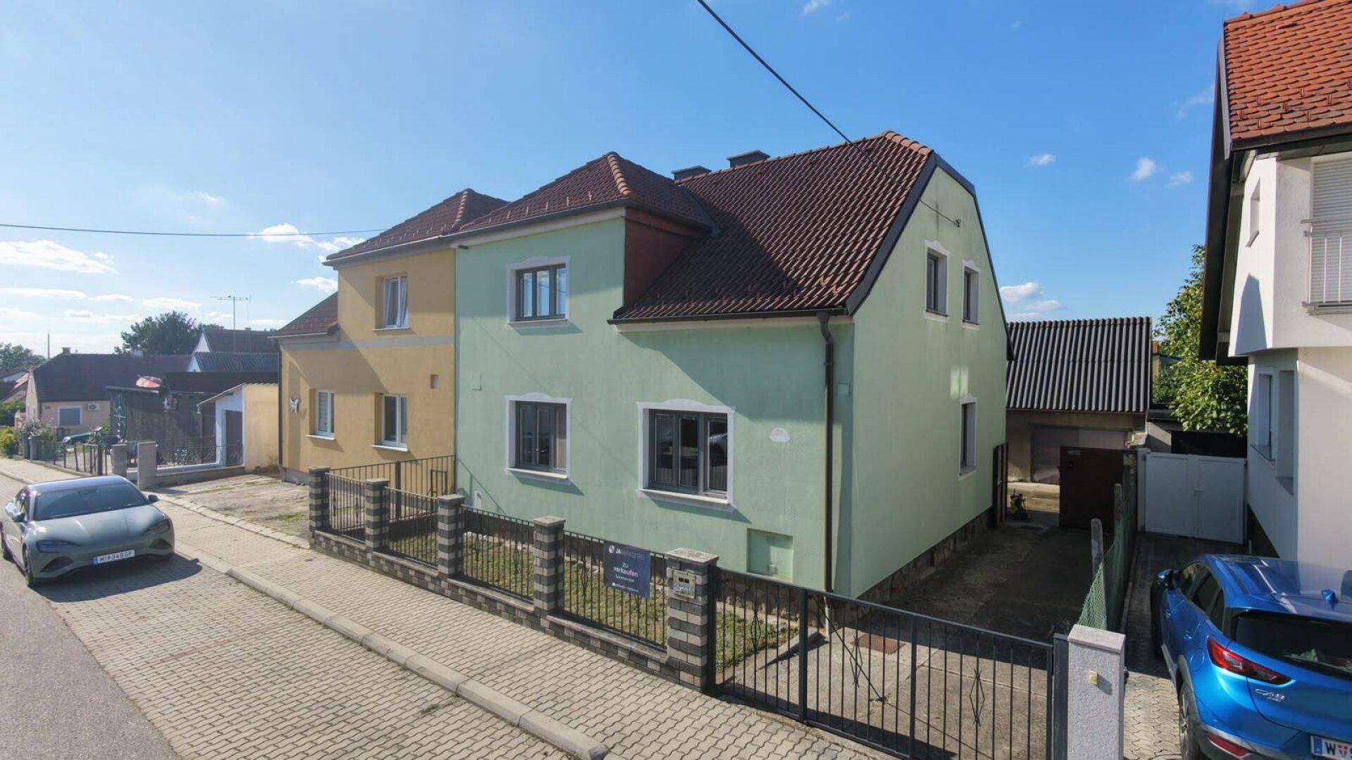 Gesamtansicht des Hauses mit angrenzendem Gebäude und gepflegtem Vorgartenbereich.