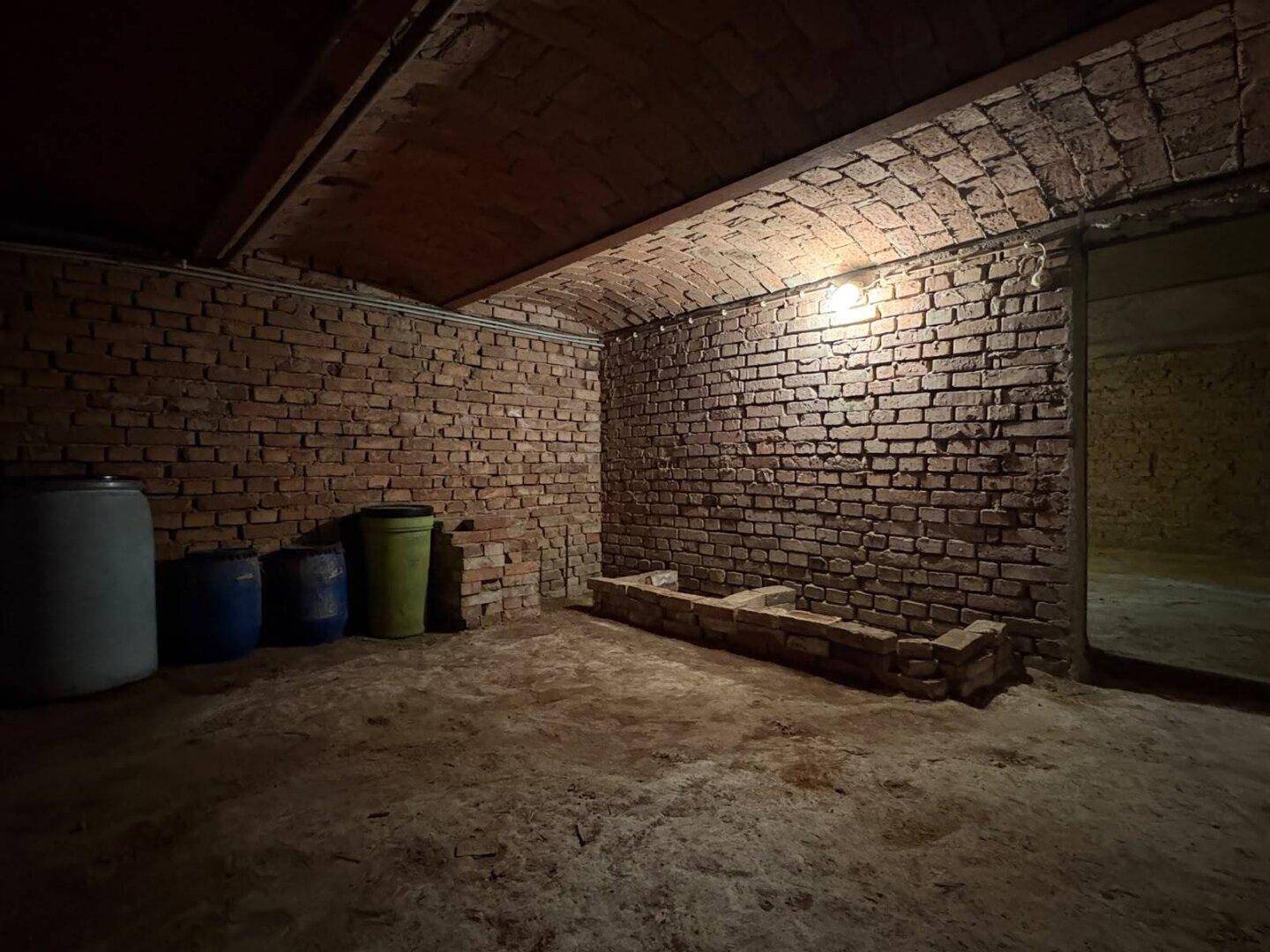 Historischer Gewölbekeller mit Ziegelwänden und Lagerfässern, rustikal und kühl.