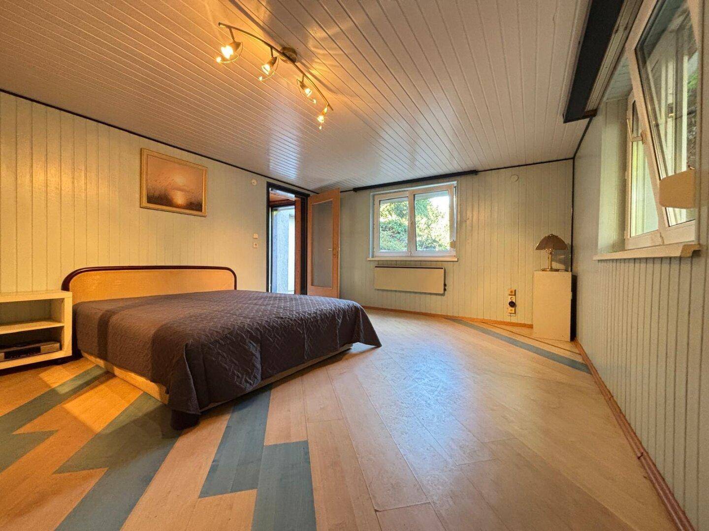 Geräumiges Schlafzimmer mit Holzboden, Holzdecken und Zugang zum Außenbereich.