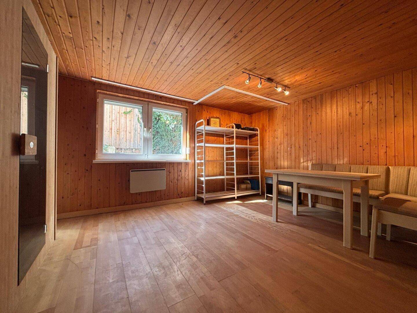 Vielseitiger Raum mit Holzverkleidung, Fenster und Stauraummöglichkeiten.
