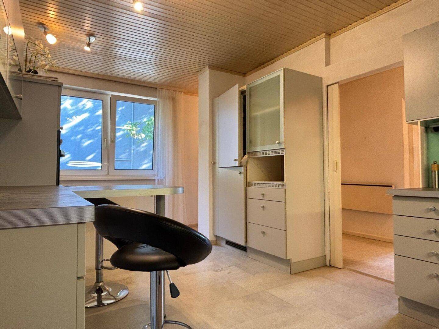 Küchenbereich mit Fenster, Frühstücksbar und Stauraum, der viel Tageslicht bietet.