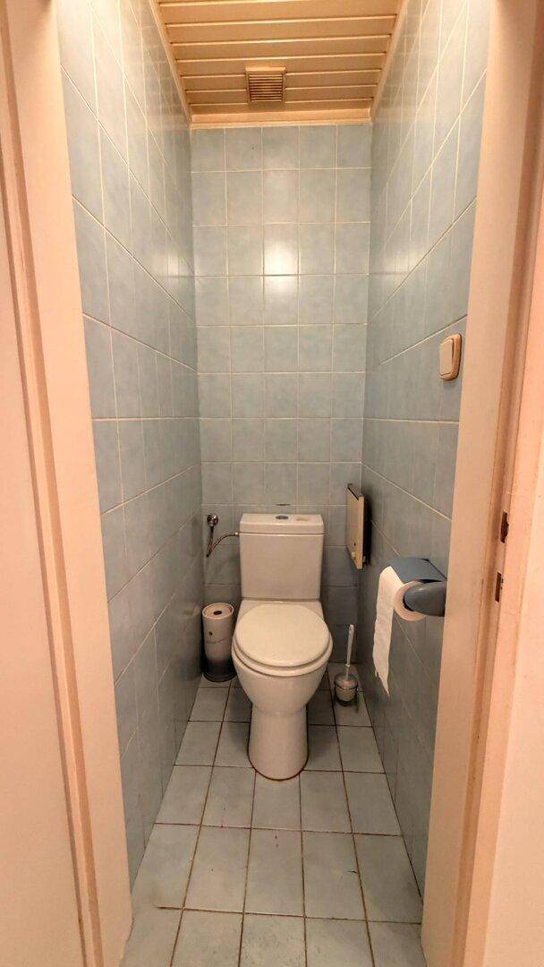 Separate Toilette mit blauen Fliesen und Holzdeckenverkleidung.