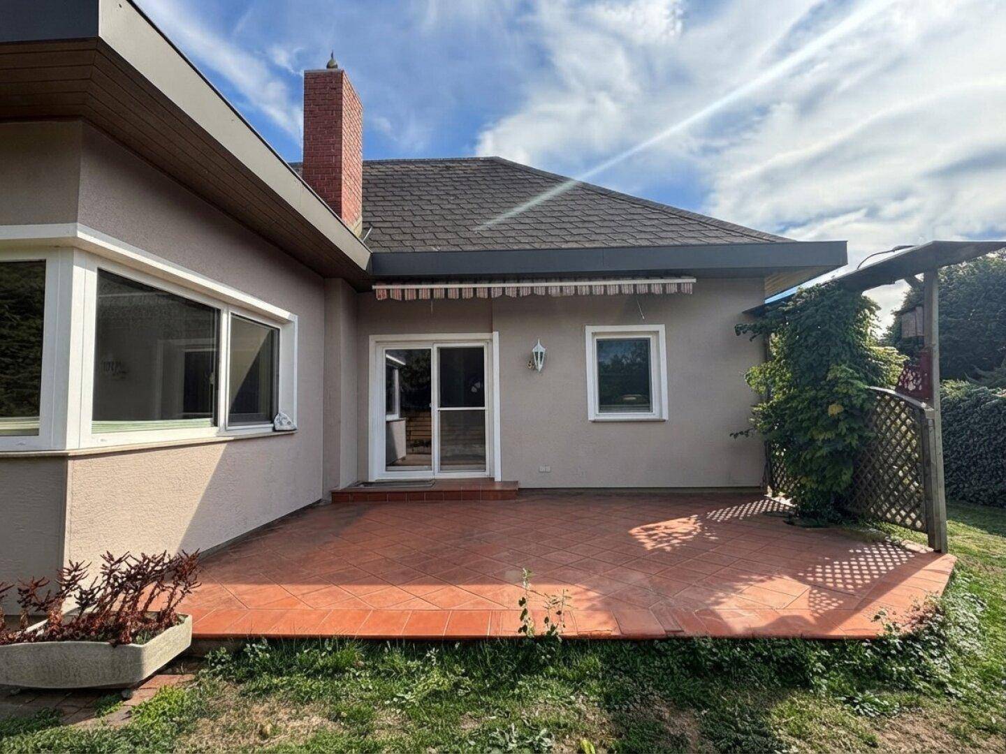 Gemütliche Terrasse mit Terrakottafliesen und Markise, angrenzend an den Garten.