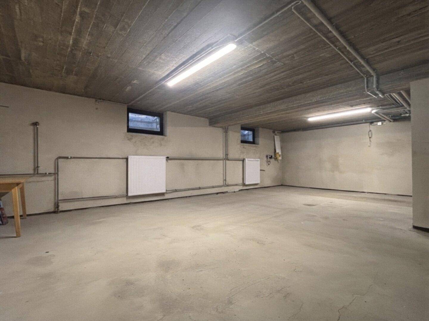 Großer Kellerraum mit Betonboden und Heizungsrohren, vielseitig nutzbar.