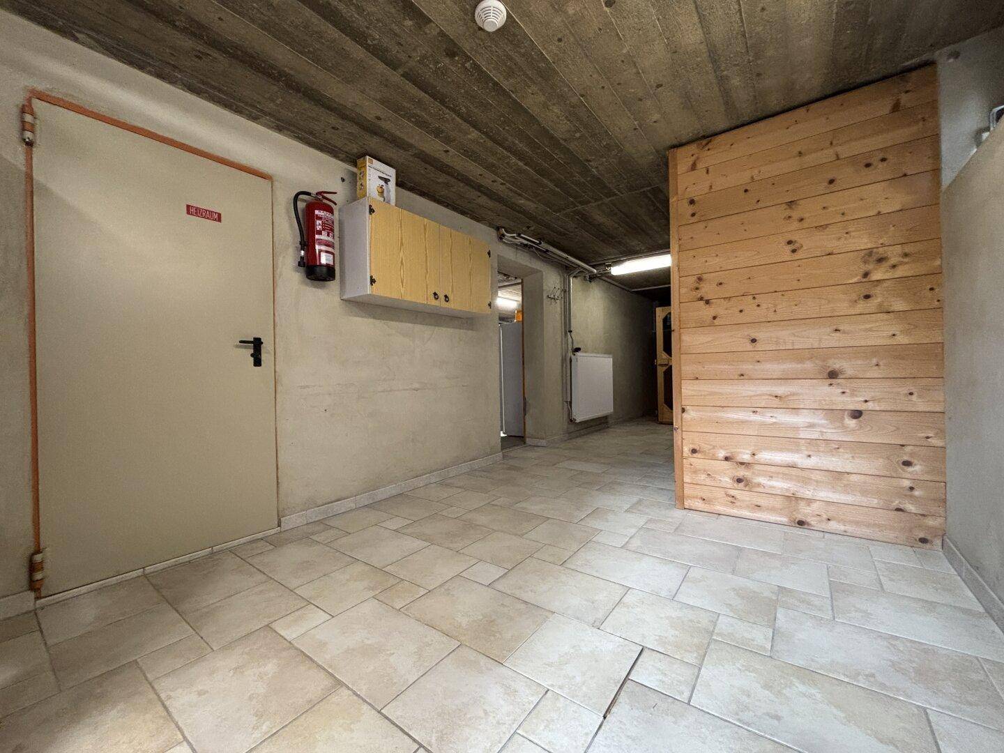 Geräumiger Kellerraum mit Fliesenboden und Holzverkleidung, ideal als Lagerfläche.