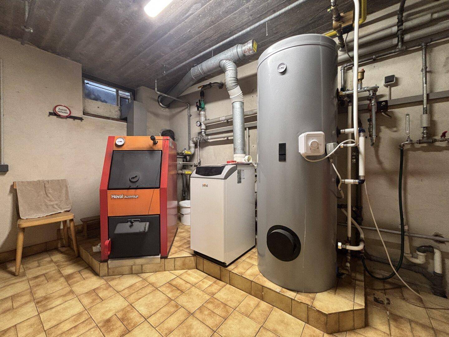 Heizungsraum im Keller mit modernen Heizungsanlagen und Warmwasserspeicher.