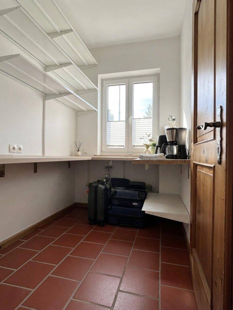 Praktischer Abstellraum mit Regalen, Fenster und Terrakottafliesen, ideal für Vorräte.