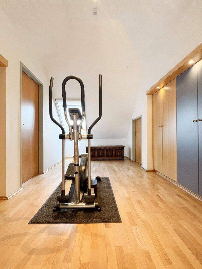 Fitnessbereich im Dachgeschoss mit Holzboden und Einbauschränken, ideal für Sport zu Hause.