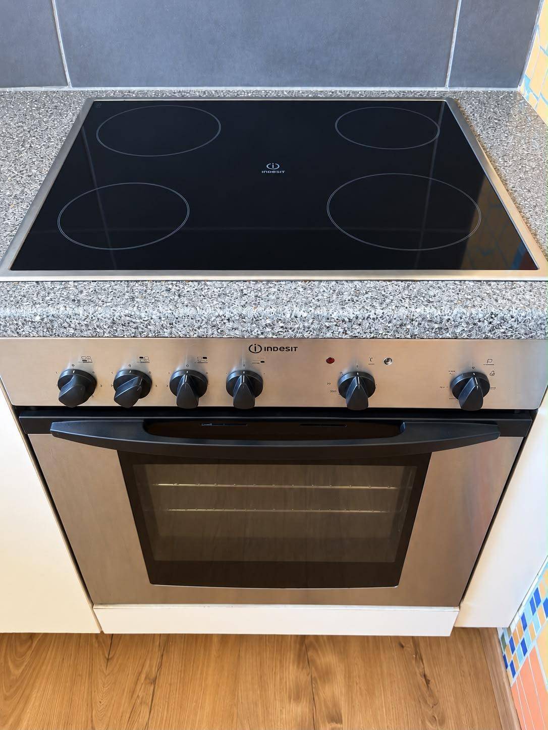 Integrierter Backofen und Cerankochfeld in einer modernen Küche mit Granitarbeitsplatte.