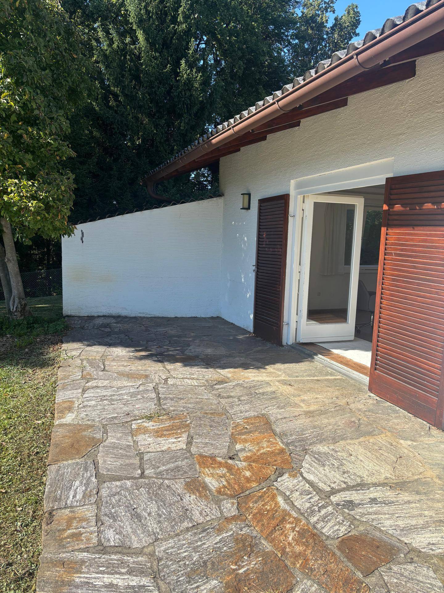 Gepflasterte Terrasse aus Natursteinplatten direkt am Haus mit Zugang zum Innenbereich.