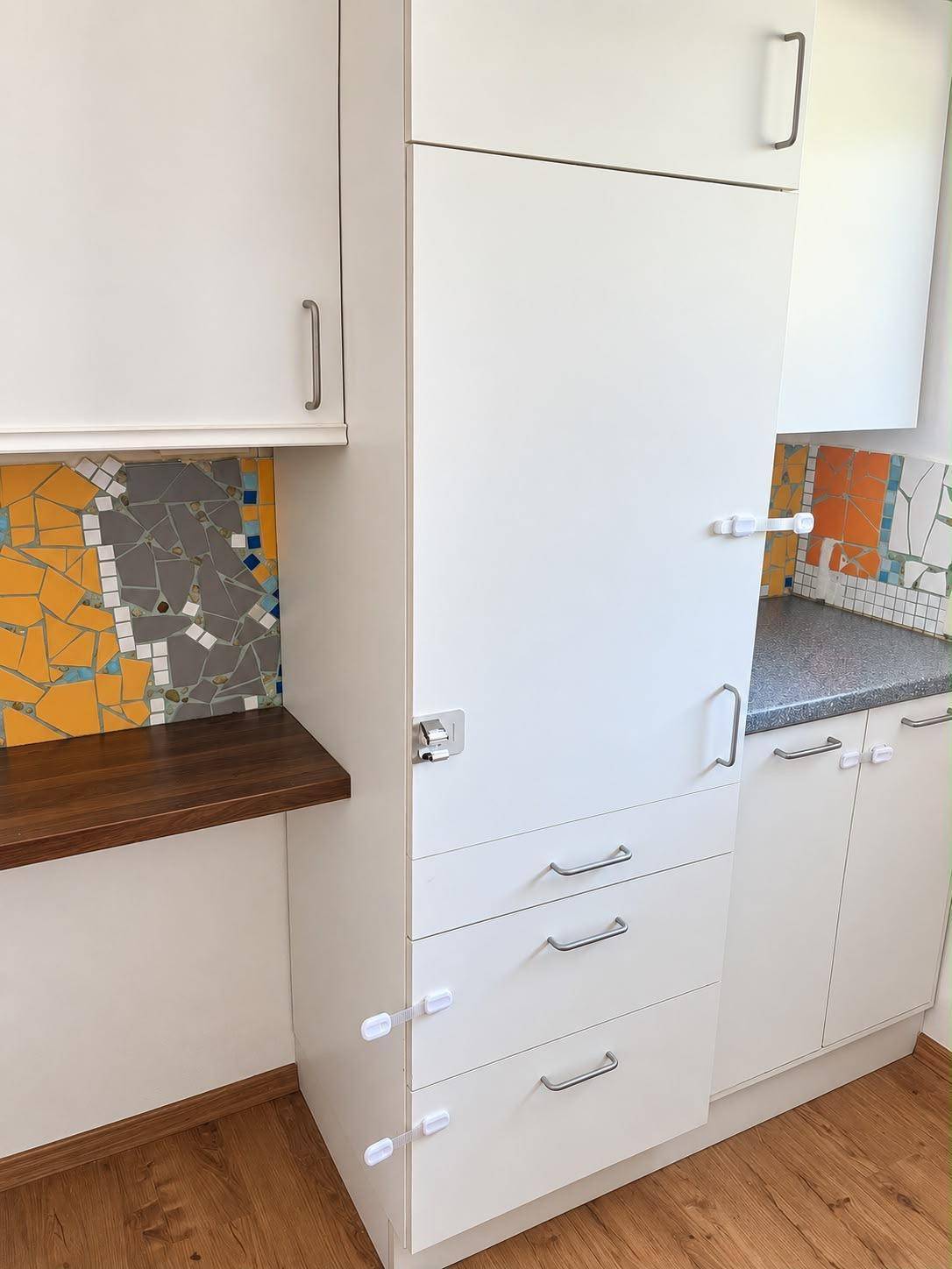 Weiße Einbauküche mit bunten Mosaikfliesen als Spritzschutz und Holztheke.