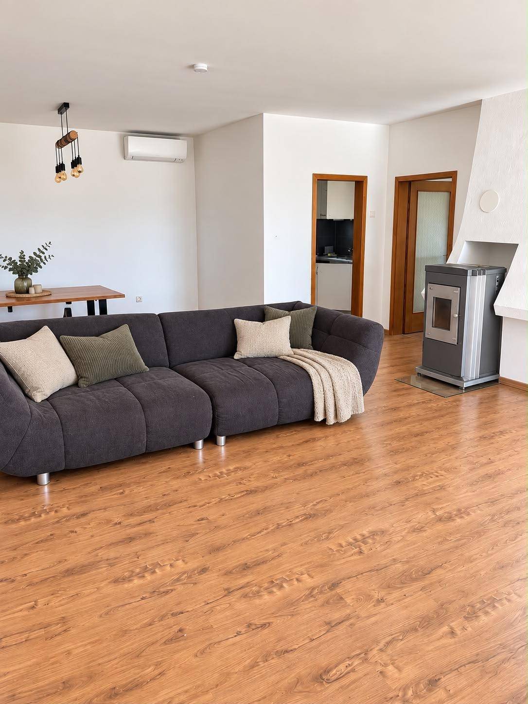 Geräumiger Wohn- und Essbereich mit Laminatboden, Kaminofen und Klimaanlage.