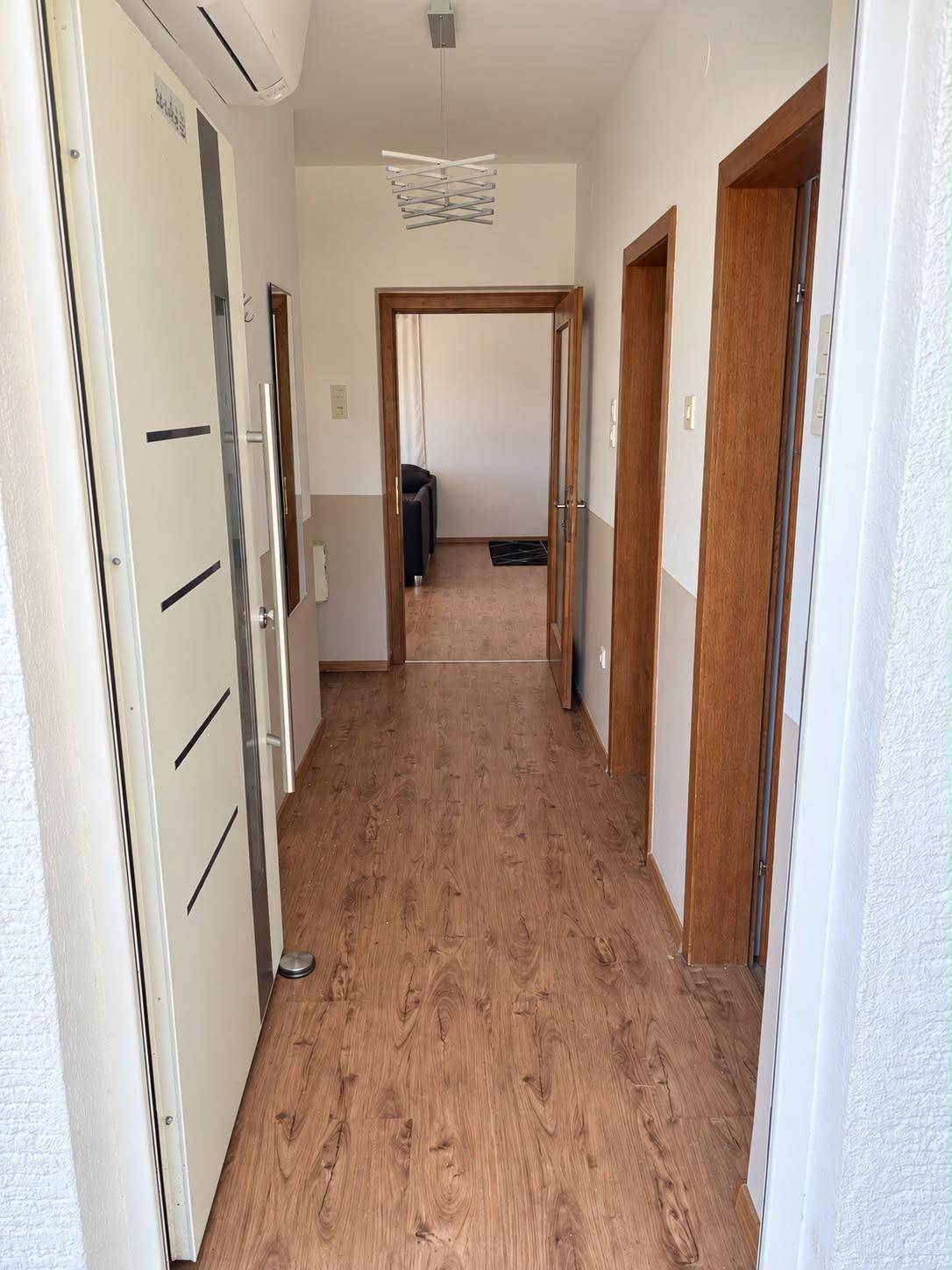 Heller Flur mit Laminatboden und Holztüren, der zu verschiedenen Räumen führt.