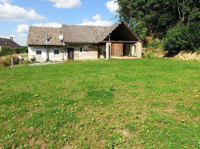 Altes Bauernhaus mit großem Gartenbereich und rustikalem Charme unter blauem Himmel.