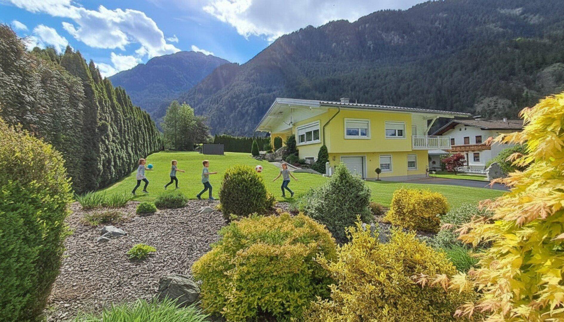Kinder spielen auf dem weitläufigen Rasen des Gartens mit beeindruckendem Bergblick im Hintergrund.