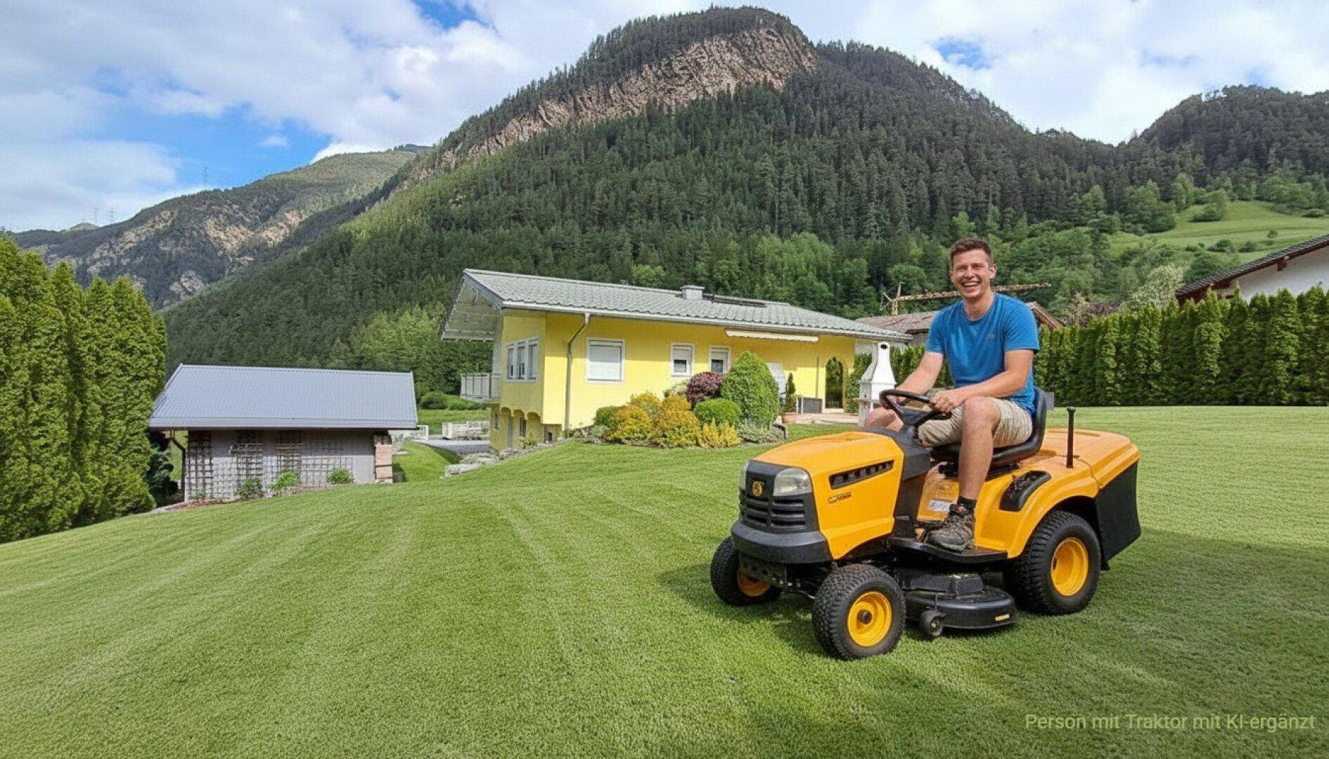 Gepflegter Rasen im weitläufigen Gartenbereich mit einem Haus und majestätischen Bergen im Hintergrund.