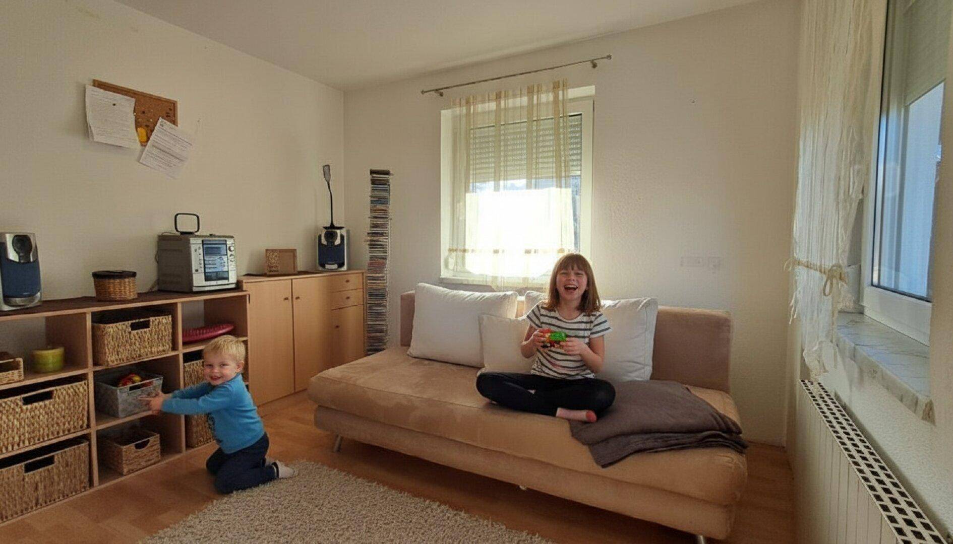 Helles Kinder- oder Gästezimmer mit Sofa, Stauraum und viel natürlichem Licht.