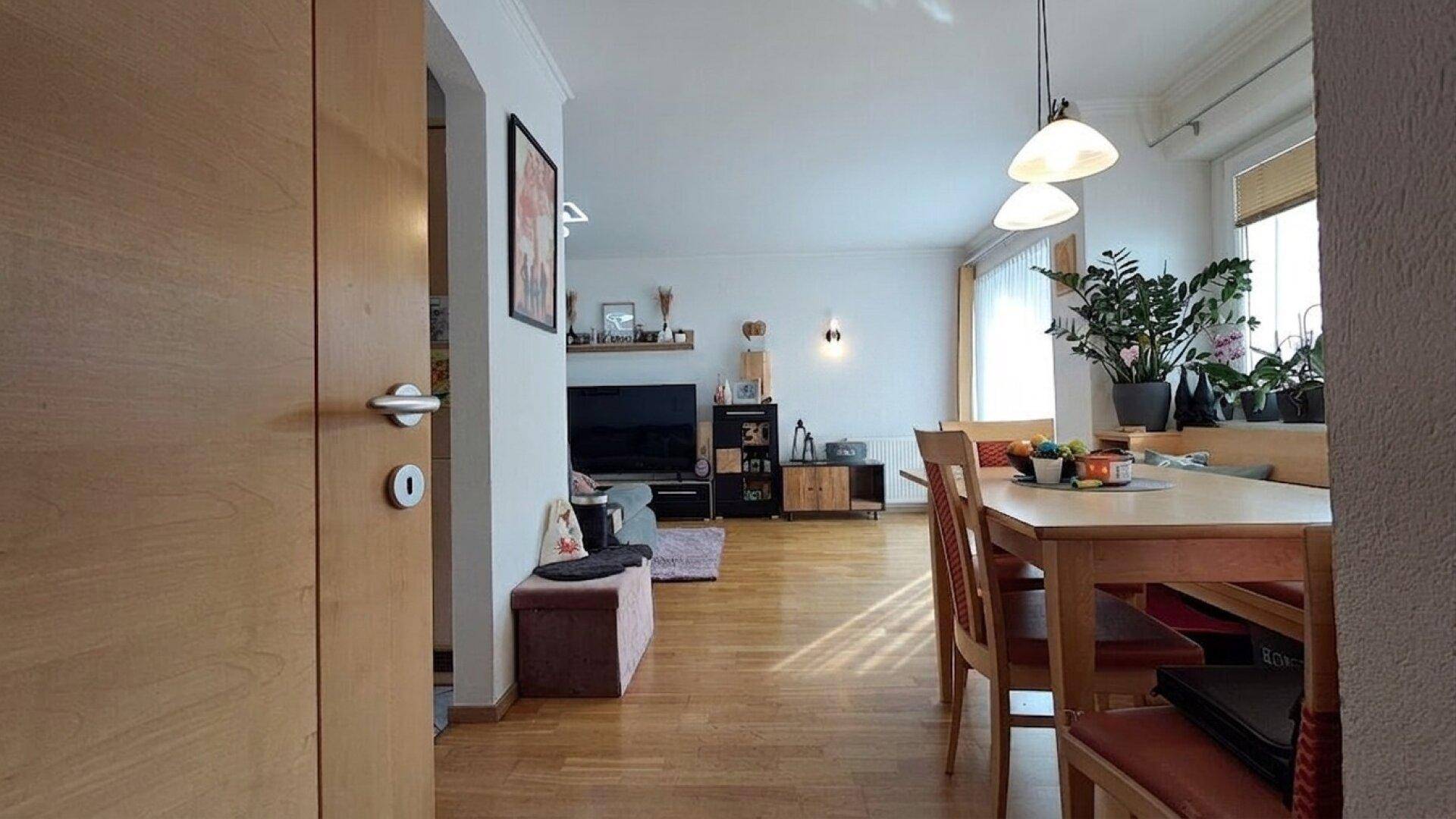 Heller Wohn- und Essbereich mit Holzfußboden, Esstisch und Blick auf den Wohnbereich mit TV.