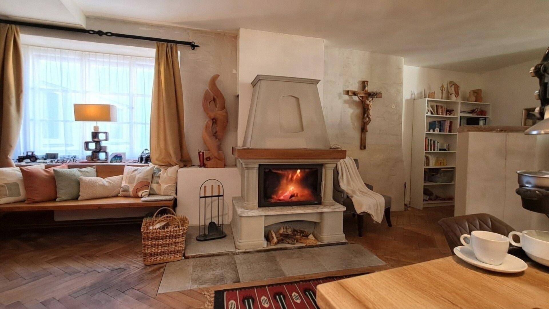 Wohnbereich mit einem Kamin, einer Holzsitzbank und traditioneller Dekoration, die eine warme Atmosphäre schafft.
