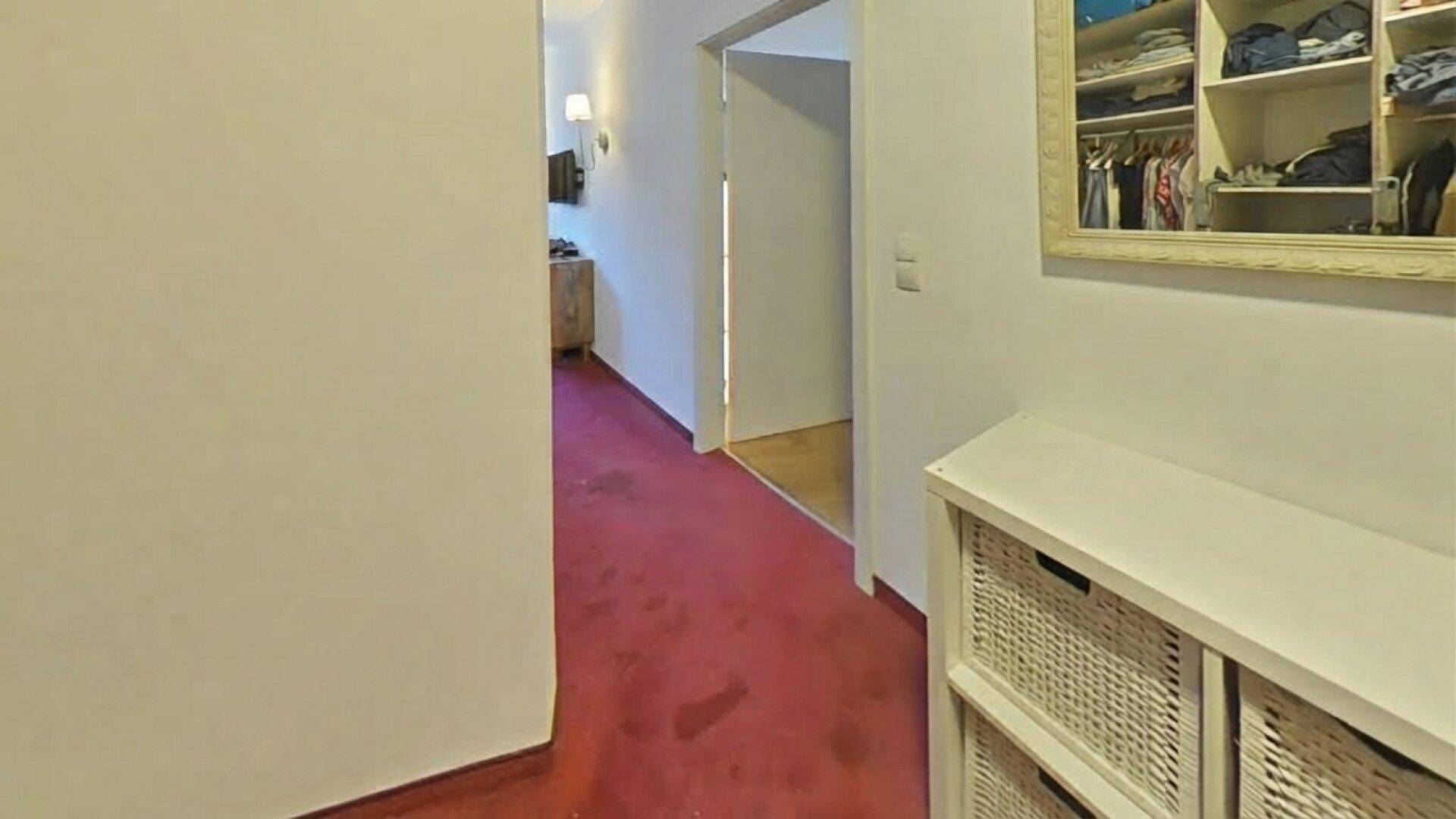 Flur mit rotem Teppichboden und einem weißen Aufbewahrungsmöbel, das zusätzlichen Stauraum bietet.