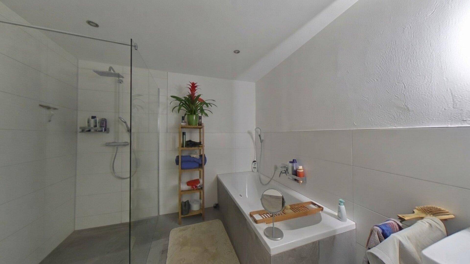 Geräumiges Badezimmer mit einer Badewanne und einer modernen, begehbaren Dusche.