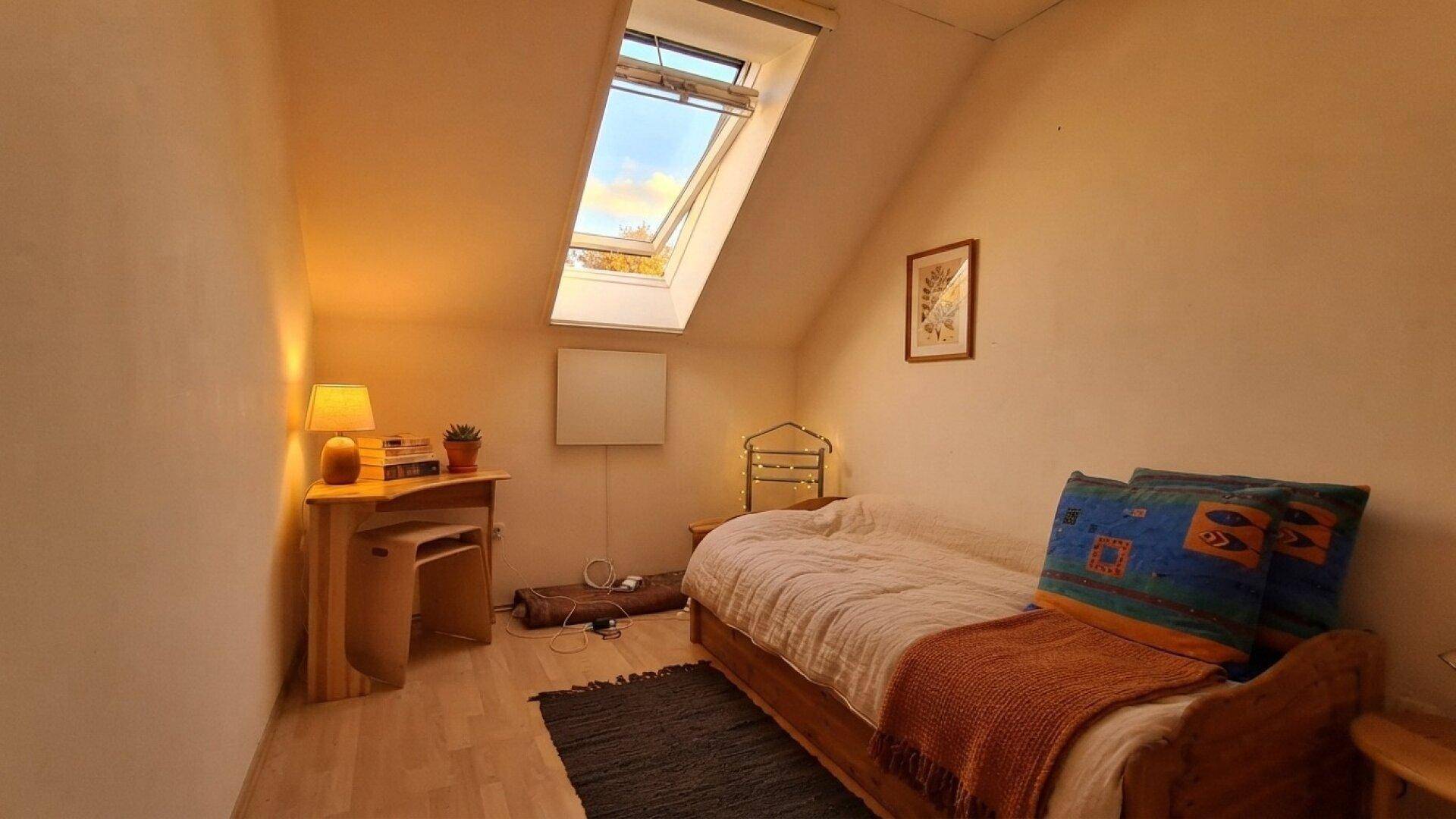 Kleines Schlafzimmer oder Arbeitszimmer im Dachgeschoss mit Einzelbett und Dachfenster.
