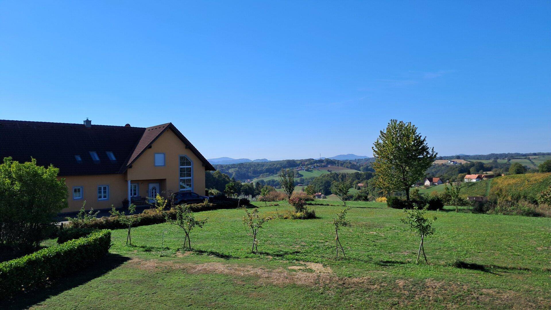 Gelbes Haus mit rotem Dach und großem Garten in ländlicher Umgebung.